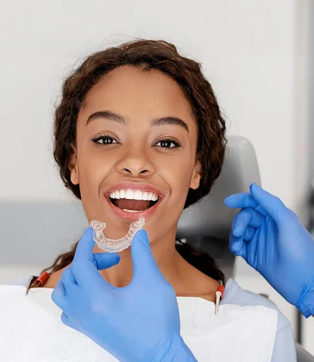 Dentist in mask treating female patient in dental chair