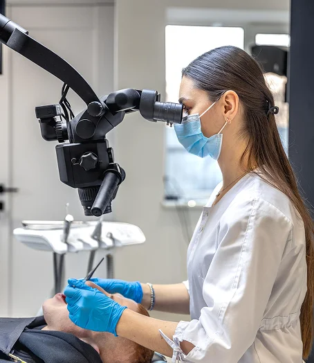 Female dentist using dental microscope during precision treatment
