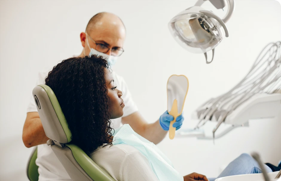 Dentist holding a tooth-shaped mirror for a female patient to check her smile after a dental procedure