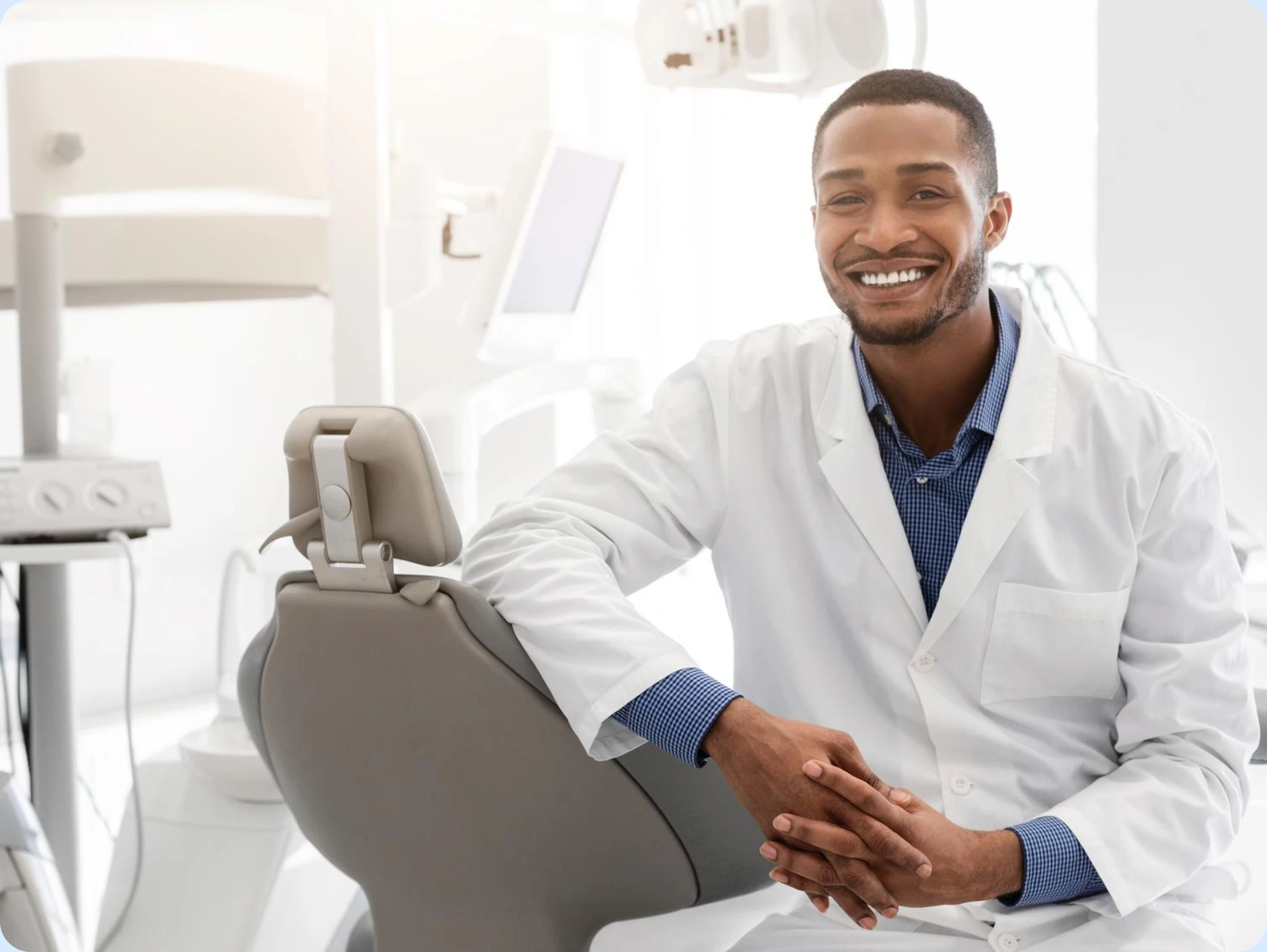 Smiling dentist in a white coat seated in a bright dental office