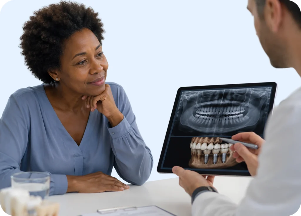 Dentist reviewing a dental implant X-ray on a tablet with a patient during an eligibility evaluation